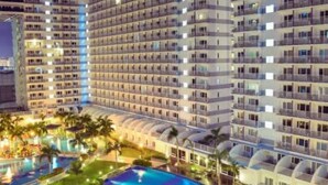 A multi-story hotel with a swimming pool and palm trees. - Ardent 1BR Condo Front of Mall of Asia Pasay City (Pasay)