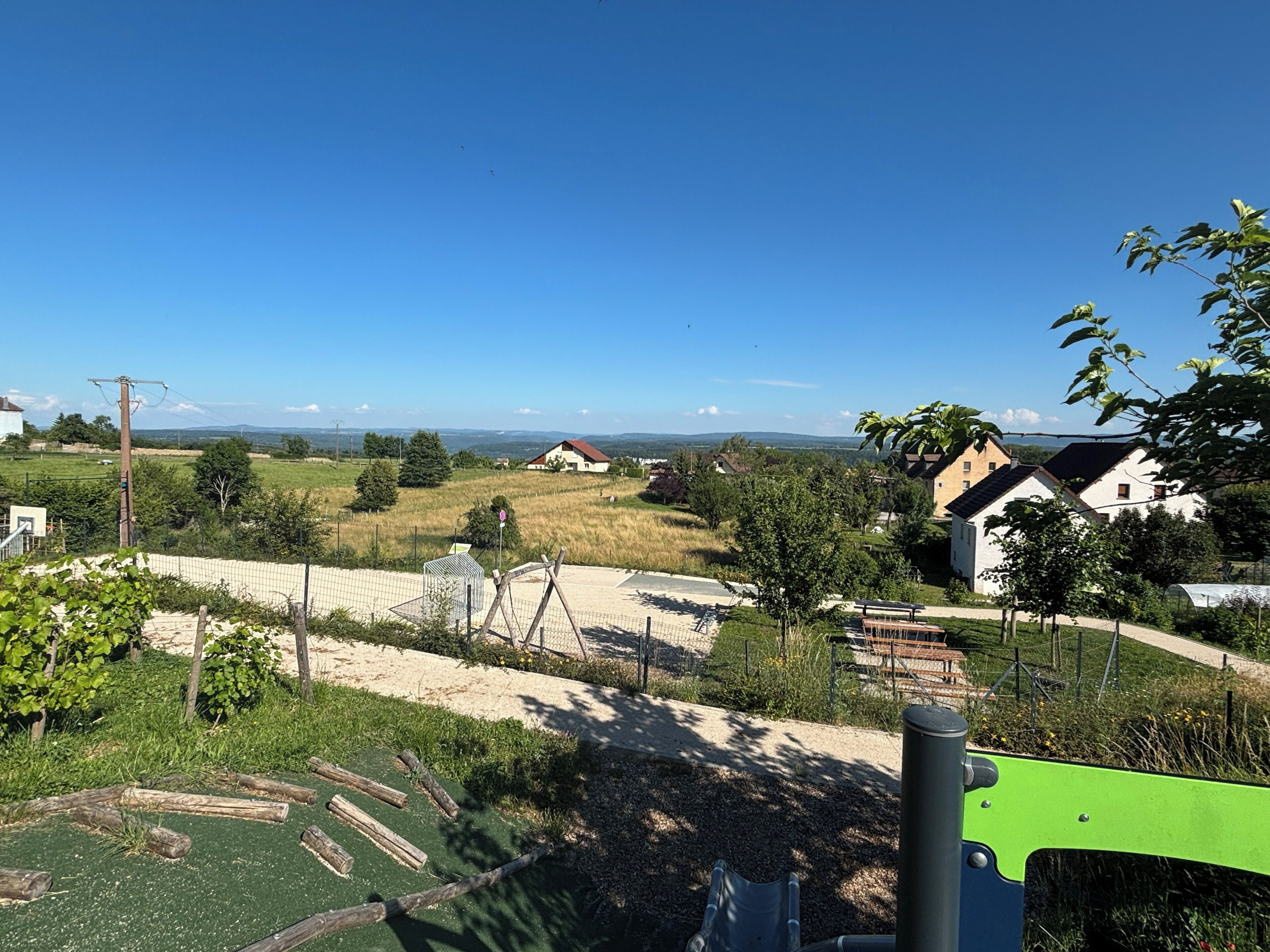 Ländliche Landschaft mit Häusern, einem Spielplatz und blauem Himmel.