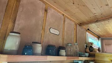 Un angolo cottura con soffitto in legno, un cartello con scritto 'CUISINE' e diversi barattoli su uno scaffale.