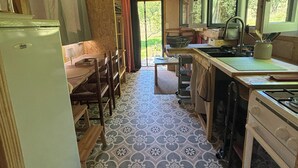 A rustic kitchen with a wooden ceiling, a refrigerator, a sink, and a window. - Hempcrete Tiny House (Malbrans)