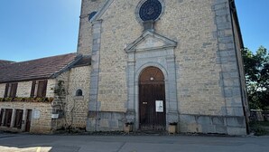 A stone church with a clock tower, a large arched entrance, and a bell tower. - Hempcrete Tiny House (Malbrans)