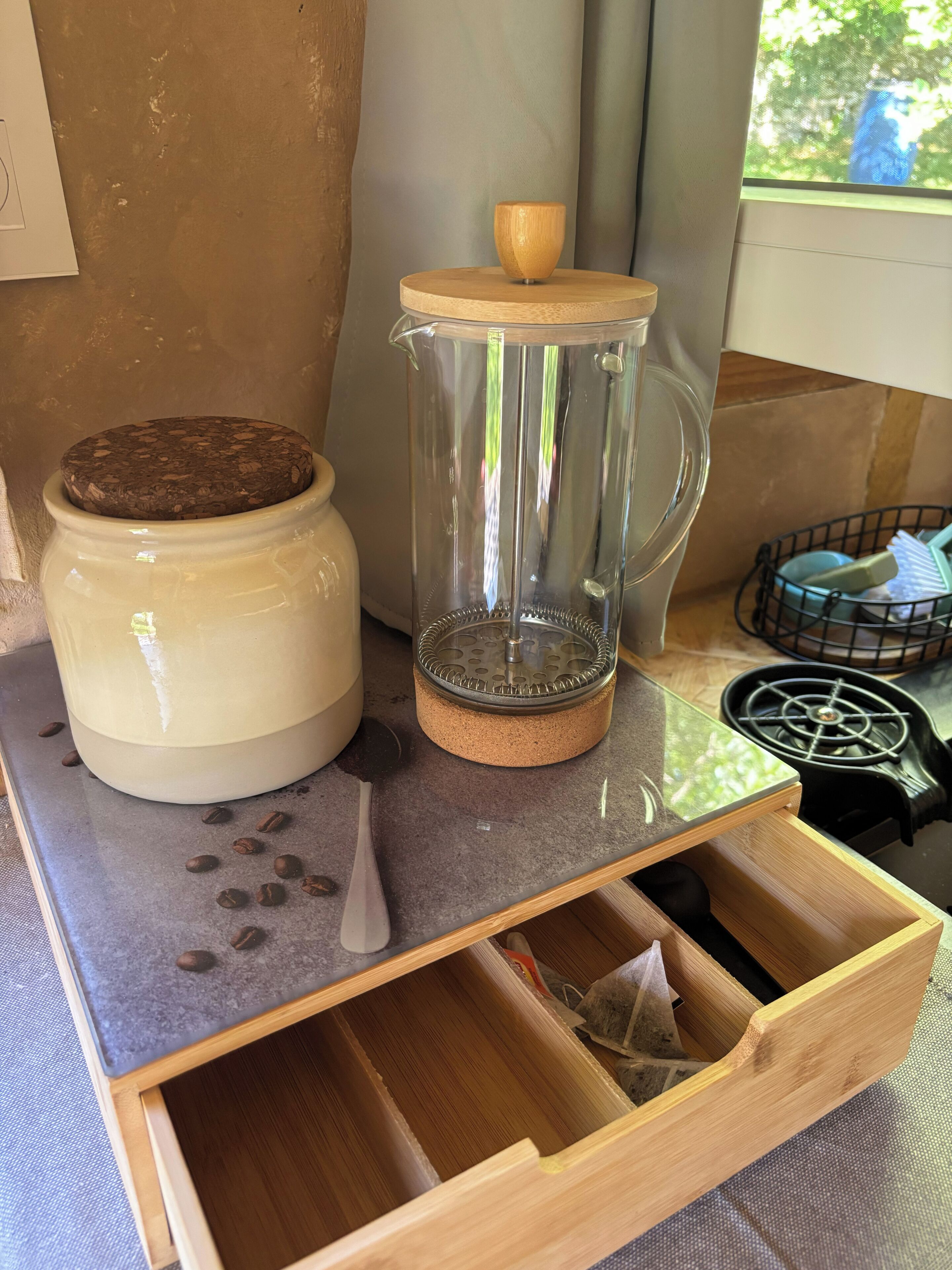 Een keukentop met een koffiemolen, een koffiepot en een lade.