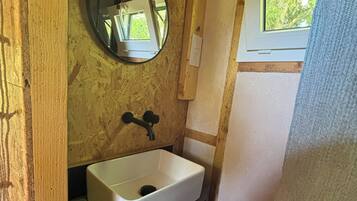 A compact bathroom with a white sink, wooden vanity, and a mirror.