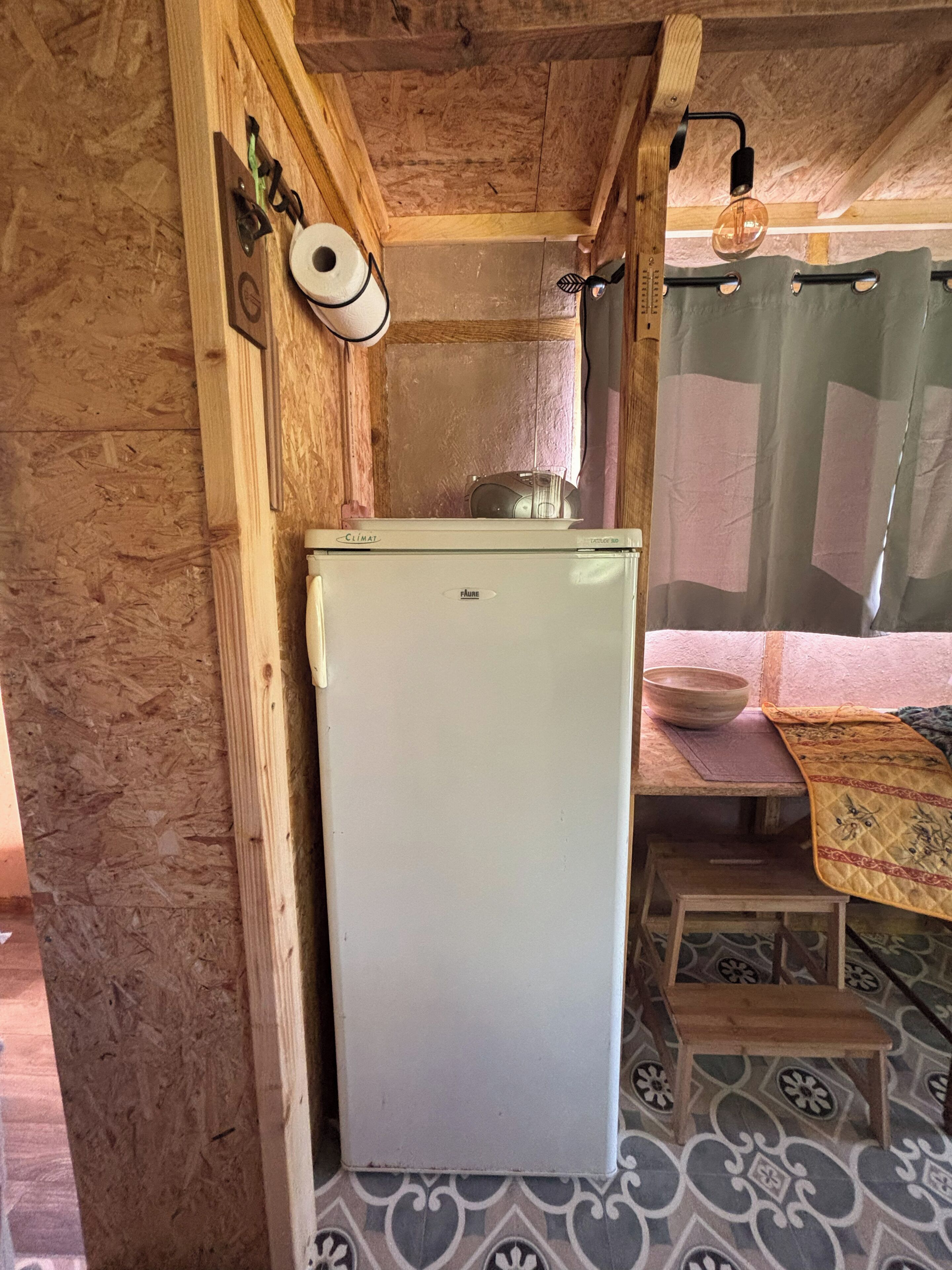 A compact kitchen with a white refrigerator, wooden cabinets, and a patterned floor.