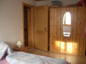 A bedroom with a bed, a nightstand, a wooden wardrobe with a mirror, and a window. - Claveniev , (Disentis/Mustér), 1036 by Interhome (Disentis)