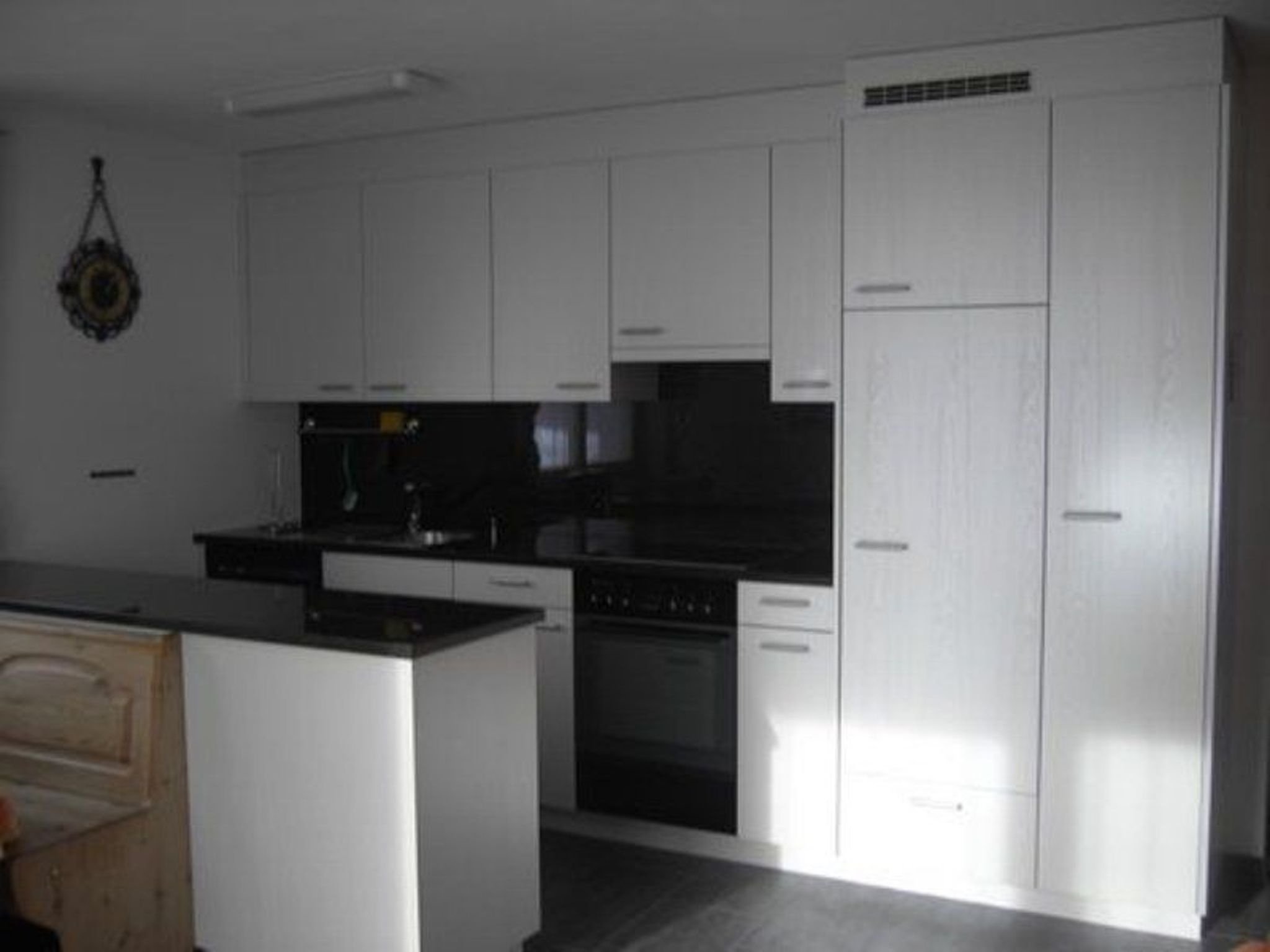 A kitchen with white cabinets, a black countertop, and a built-in oven.