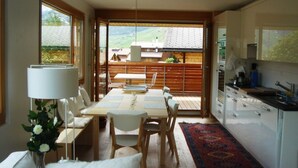 A modern kitchen with a dining area, large windows, and a view of a mountain landscape. - Tgèsa Muntaniala Stamm, (Sedrun), 198.02 by Interhome (Sedrun)