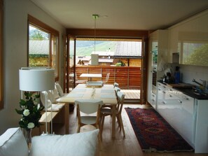 A modern kitchen with a dining area, large windows, and a view of a mountain landscape. - Tgèsa Muntaniala Stamm, (Sedrun), 198.02 by Interhome (Sedrun)