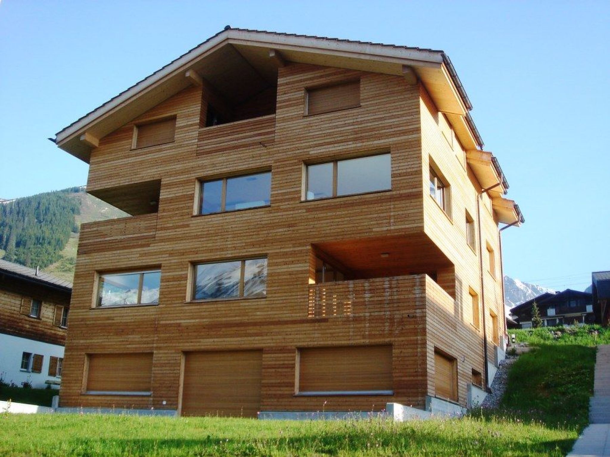 Un edificio de madera de varios pisos con balcones, con montañas al fondo.