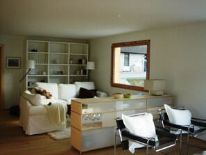 A modern living room with a sofa, a coffee table, a bookshelf, and a window with a view. - Tgèsa Muntaniala Stamm, (Sedrun), 198.02 by Interhome (Sedrun)