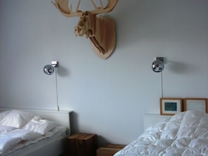 Ein Hotelzimmer mit zwei Betten, einem aufgehängten Hirschgeweih und zwei Wandleuchten.