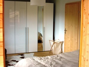 A bedroom with a bed, a wardrobe, a mirror, and a door. - Tgèsa Muntaniala Stamm, (Sedrun), 198.02 by Interhome (Sedrun)