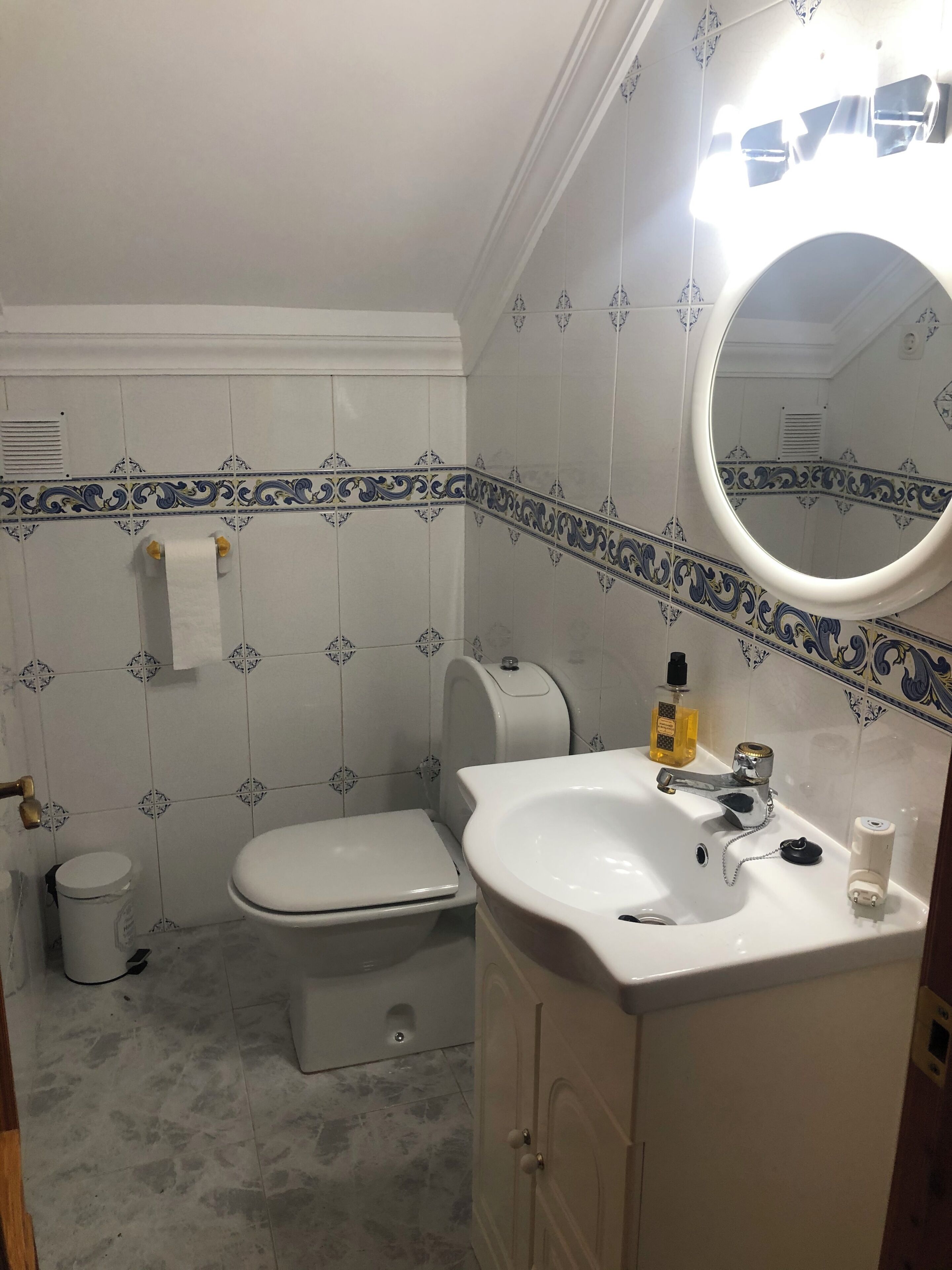 Un baño con inodoro, lavamanos y espejo.