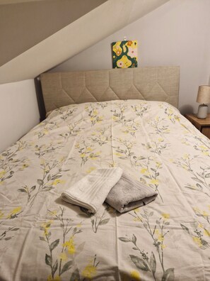 A bed with a floral bedspread, a headboard, a nightstand with a lamp, and a painting on the wall. - Gorgeous apartment close to the sea with private beach (Antalya)