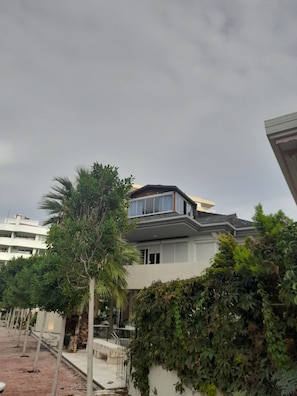 A modern residential building with a flat roof, large windows, and a balcony. - Gorgeous apartment close to the sea with private beach (Antalya)
