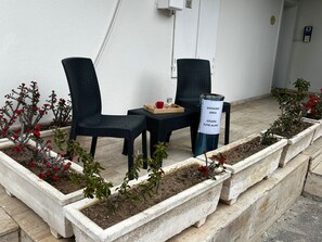An outdoor seating area with two chairs, a table, and a smoking area sign. - Gorgeous apartment close to the sea with private beach (Antalya)