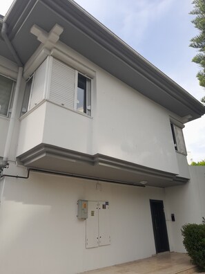A two-story building with a flat roof, a visible window with blinds, and a door. - Gorgeous apartment close to the sea with private beach (Antalya)
