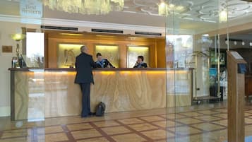 A hotel reception desk with a marble floor, a chandelier, and a sign indicating 'Best Western' branding.