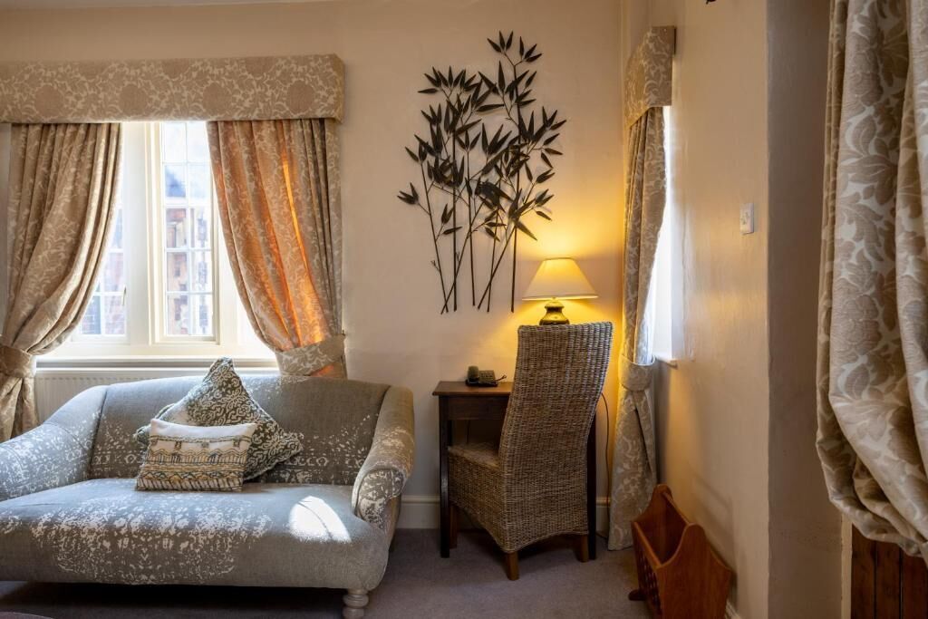 A room with a sofa, a chair, a lamp, and a wall decoration.
