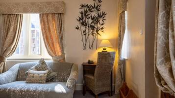 A room with a sofa, a chair, a lamp, and a wall decoration.