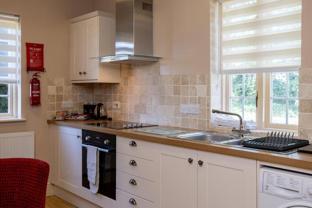 A kitchen with a stove, oven, dishwasher, and a window with blinds.
