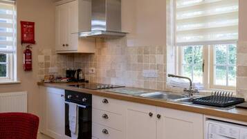 A kitchen with a stove, oven, dishwasher, and a window with blinds.