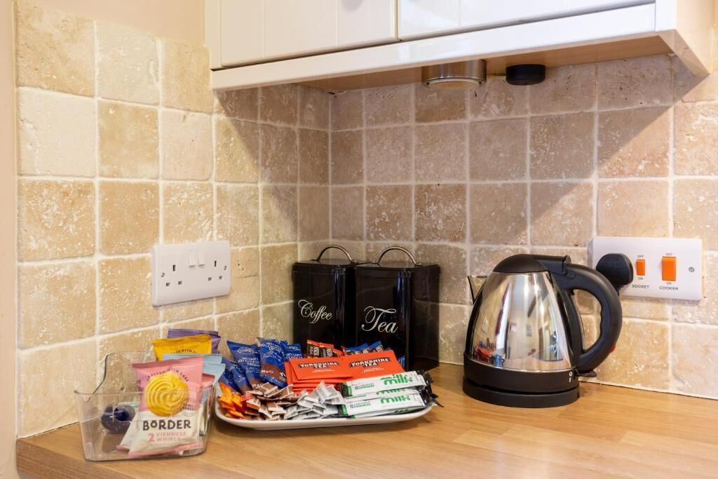 A kitchen counter with a coffee maker, tea bags, and assorted snacks.