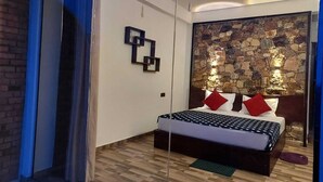 Een moderne slaapkamer met een stenen muur, een bed met een gebedrukte sprei en een geometrisch kunstwerk aan de wand.