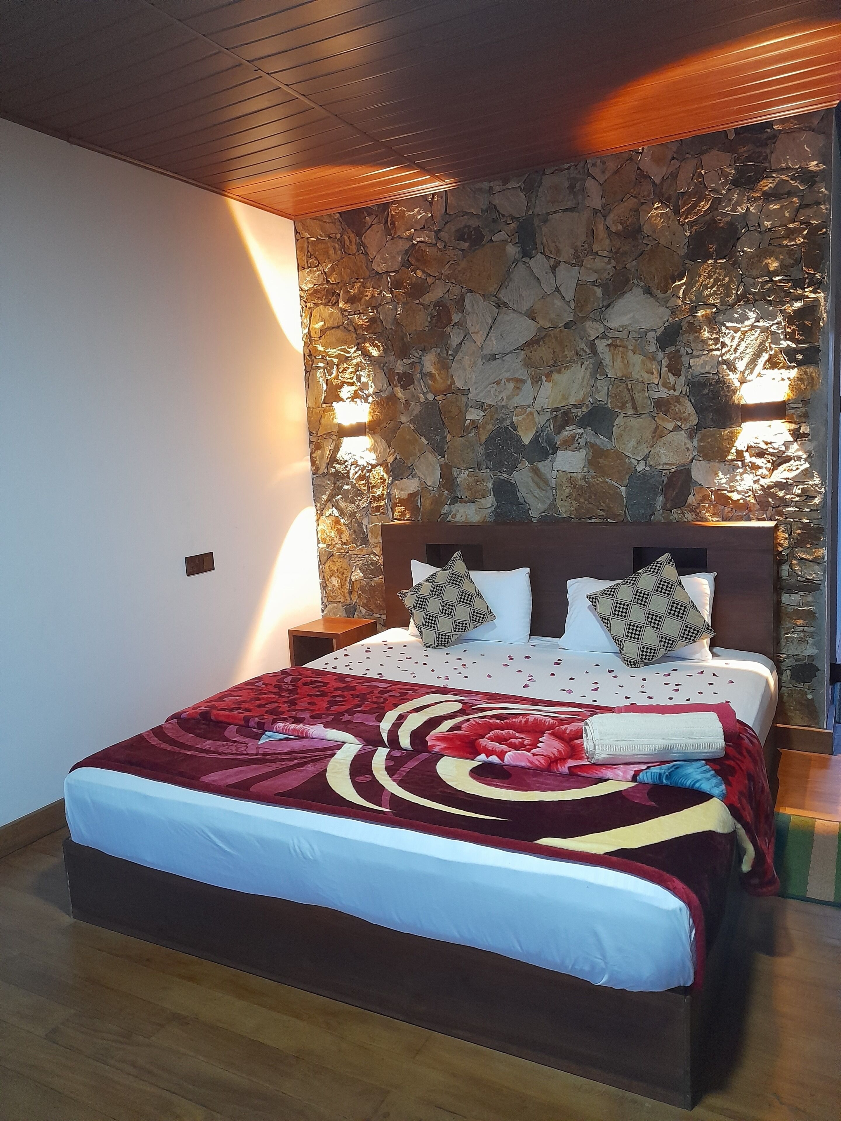 Un lit avec une couvre-lit à motifs, deux oreillers et une tête de lit en bois.
