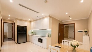 Una cucina moderna con mobili bianchi, forno integrato e zona pranzo con tavolo in legno e sedie bianche.