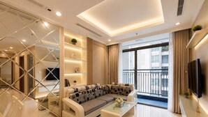 Un soggiorno moderno con un divano componibile, un tavolino da caffè e una televisione. Include un balcone con ringhiera e vista sulla città.