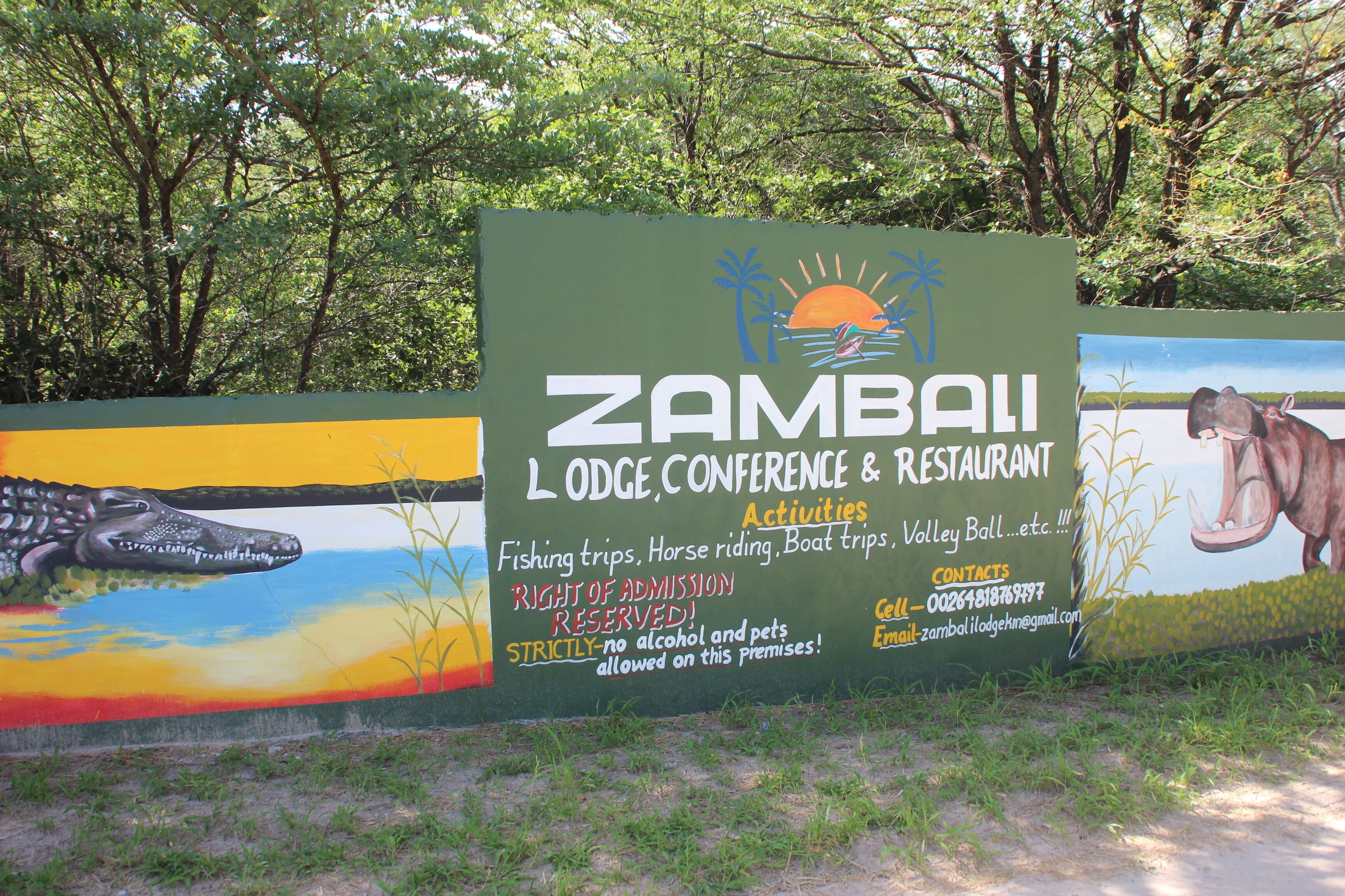 A sign for Zambali Lodge, Conference & Restaurant, listing activities like fishing trips and horse riding.