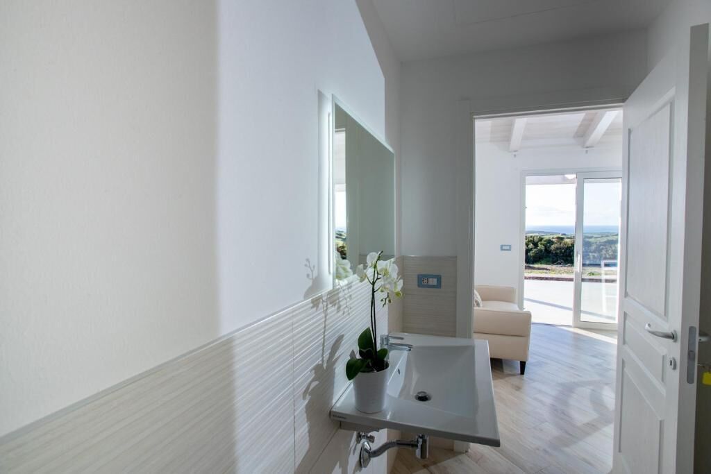 A modern bathroom with a sink, mirror, and potted orchid.