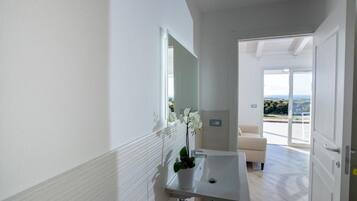 A modern bathroom with a sink, mirror, and potted orchid.