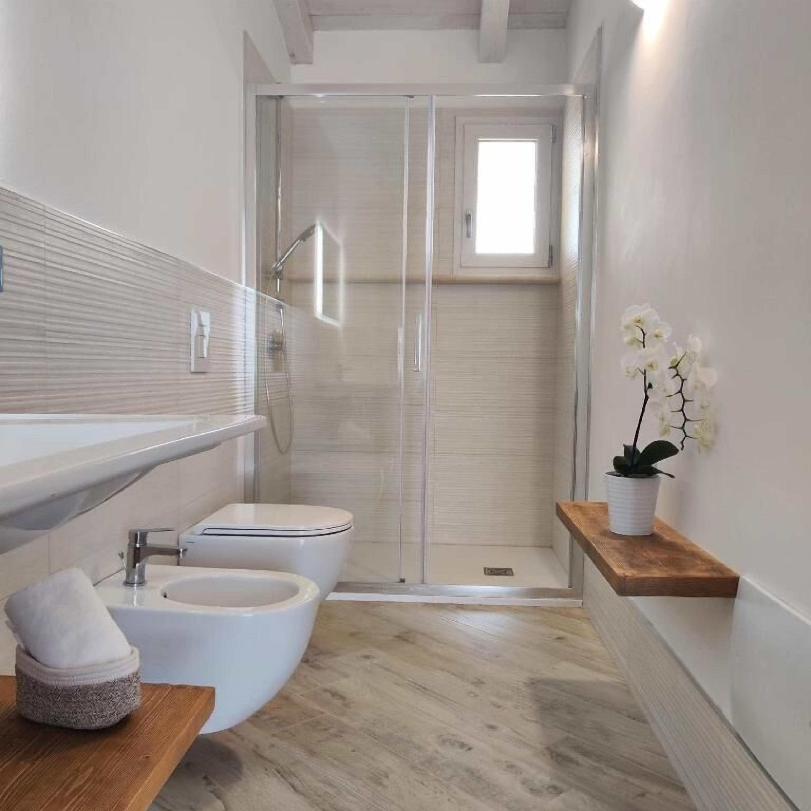 Un baño moderno con ducha, inodoro, bidé y tocador de madera.