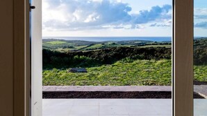 A view through a doorway to a landscape with rolling hills and a distant horizon.