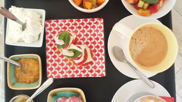 A tray with various food items including toast, fruit, a bowl of rice, a plate of meat, a cup of coffee, and a small bowl of sauce.