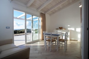 Un interior moderno con zona de comedor, un sofá y vistas a través de amplios ventanales.
