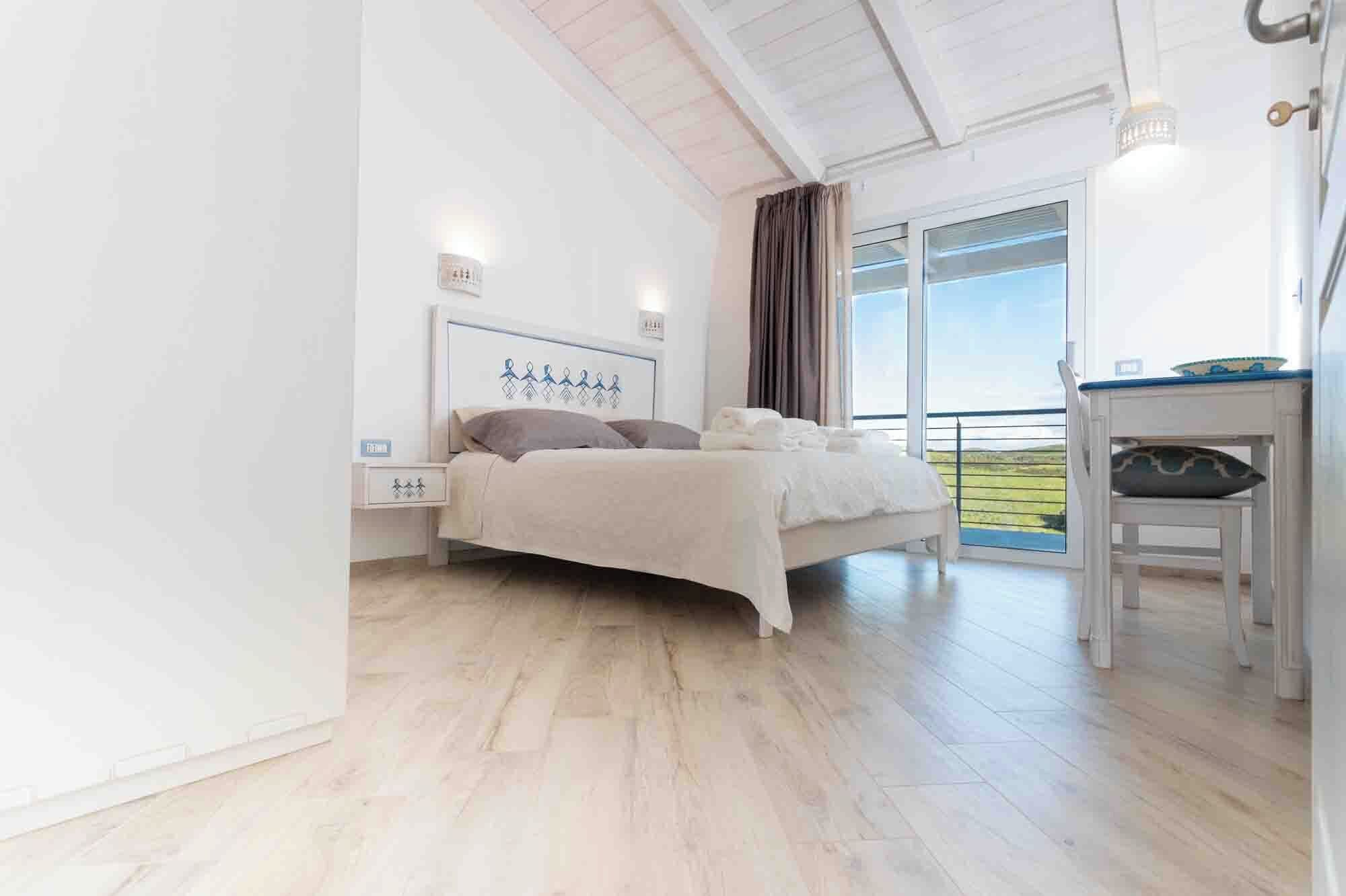 Un dormitorio con cama, mesita de noche y vistas al exterior.