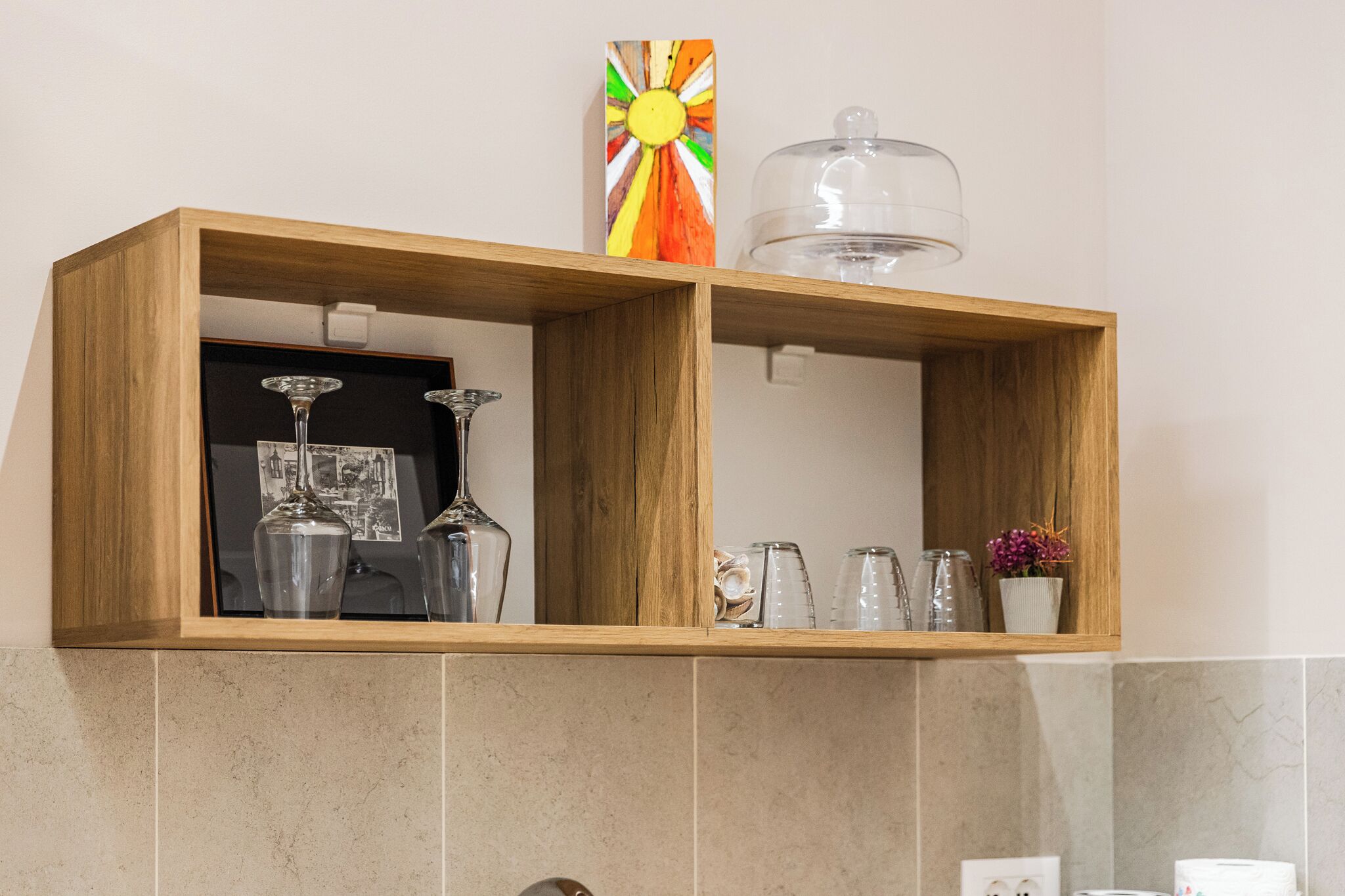 A wooden shelf with glassware and a decorative item.