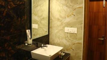 Un baño con pared de mármol, un lavabo y un espejo.