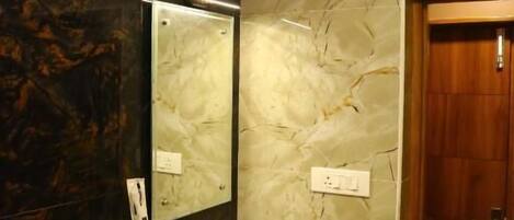 Une salle de bain avec un mur en marbre, un lavabo et un miroir.