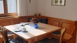 Een eetgedeelte met een houten tafel, stoelen en een bank.