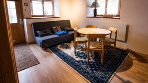 A cozy room with a sofa, a small round table, and two chairs. There are two windows with curtains, a lamp on the table, and a rug on the floor. - Ferienwohnungen Felder, (Splügen), by Interhome (Splügen)