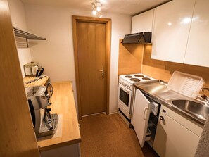 Eine kleine Küche mit Herd, Backofen, Spüle und einer Kaffeemaschine.