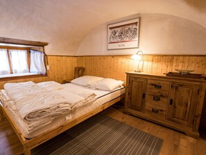 A single bed with a wooden headboard, a bedside table with a lamp, and a framed artwork above the bed. - Ferienwohnungen Felder, (Splügen), by Interhome (Splügen)