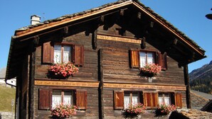 A traditional wooden chalet with multiple windows, flower boxes, and a clear sky in the background. - Ferienwohnungen Felder, (Splügen), by Interhome (Splügen)