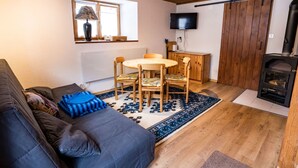 A cozy living room with a sofa, a round wooden table, and a fireplace. - Ferienwohnungen Felder, (Splügen), by Interhome (Splügen)