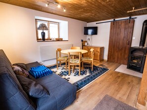 A cozy living room with a sofa, a round wooden table, and a fireplace. - Ferienwohnungen Felder, (Splügen), by Interhome (Splügen)