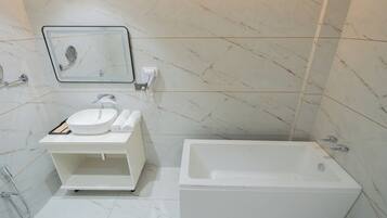 A modern bathroom with a white sink, mirror, and a standalone bathtub.